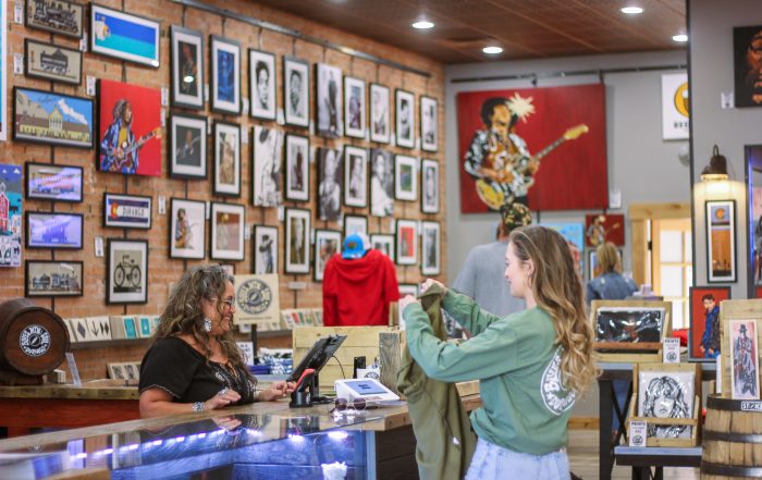 Person checking out a t-shirt at a shop counter.