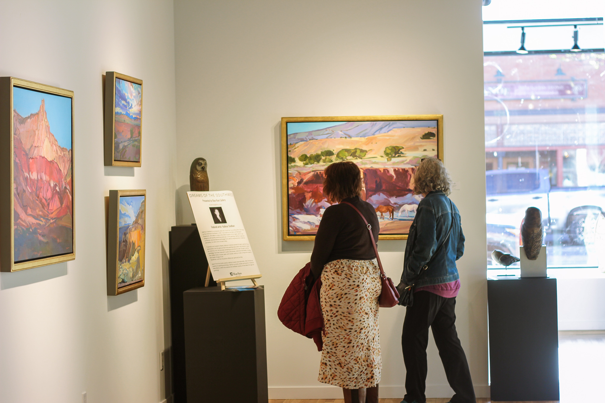 Two women staring a paintings with backs to viewer.