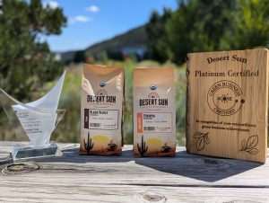 Desert Sun Coffee Photograph of two bags of coffee beans and two awards on top of a wooden ledge.