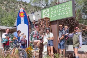 Durango Outdoor Exchange A group photo with 8 people standing in front of a sign that reads "Durango Outdoor Exchange"